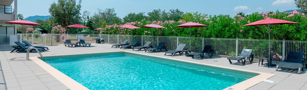 Piscine avec transats et parasols rouges