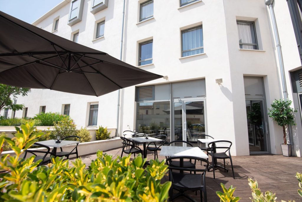 Terrasse avec tables et chaises sous de grands parasols.