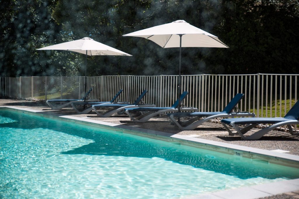 Transats et parasols au bord de la piscine extérieure du Comfort Aparthotel Toulouse Métropole.