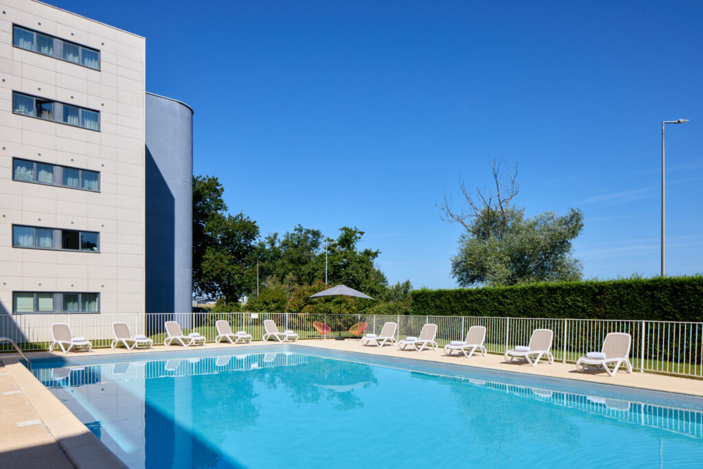 Piscine extérieure Zenitude Hôtel-Résidences Bordeaux - Aéroport avec transats et verdure