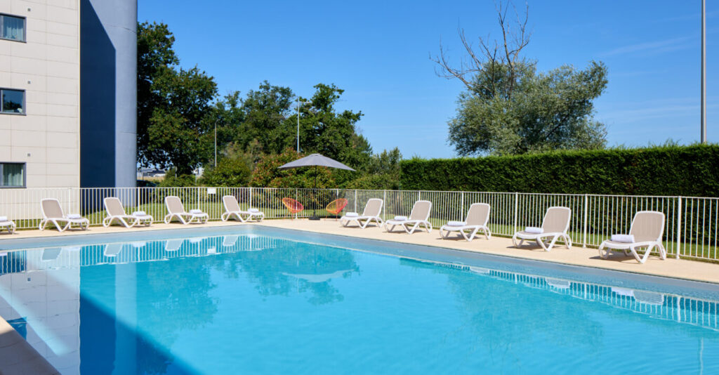 Piscine extérieure Zenitude Hôtel-Résidences Bordeaux - Aéroport avec transats et verdure