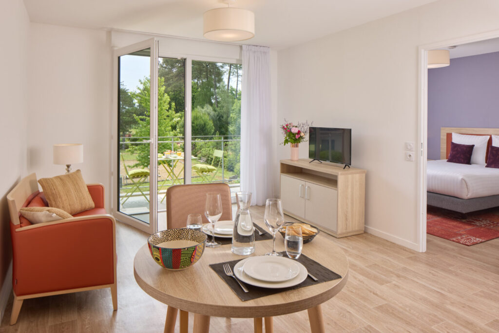 Bright living room with television and sitting area. It opens onto the balcony and is adjacent to the bedroom.