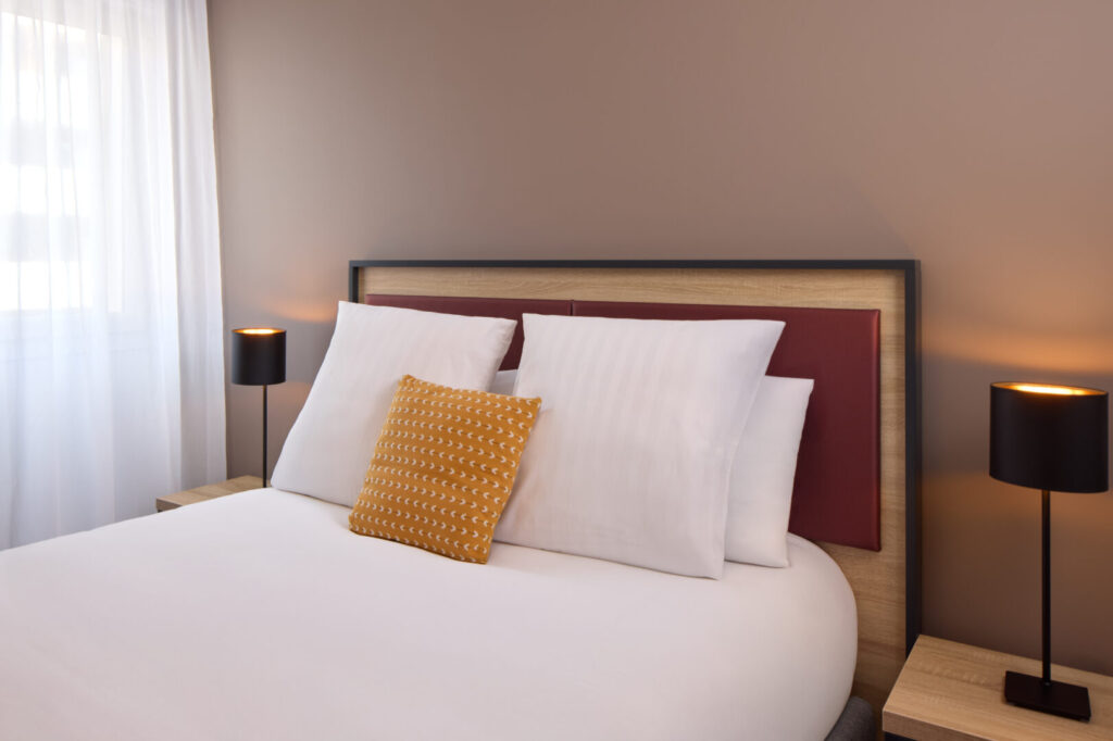 Chambre double moderne avec tête de lit design et éclairage d’ambiance à la résidence Zenitude Perpignan.