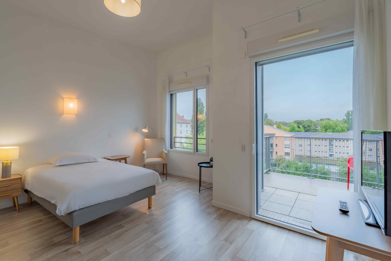 Chambre avec lit double, grande baie vitrée donnant sur le balcon.