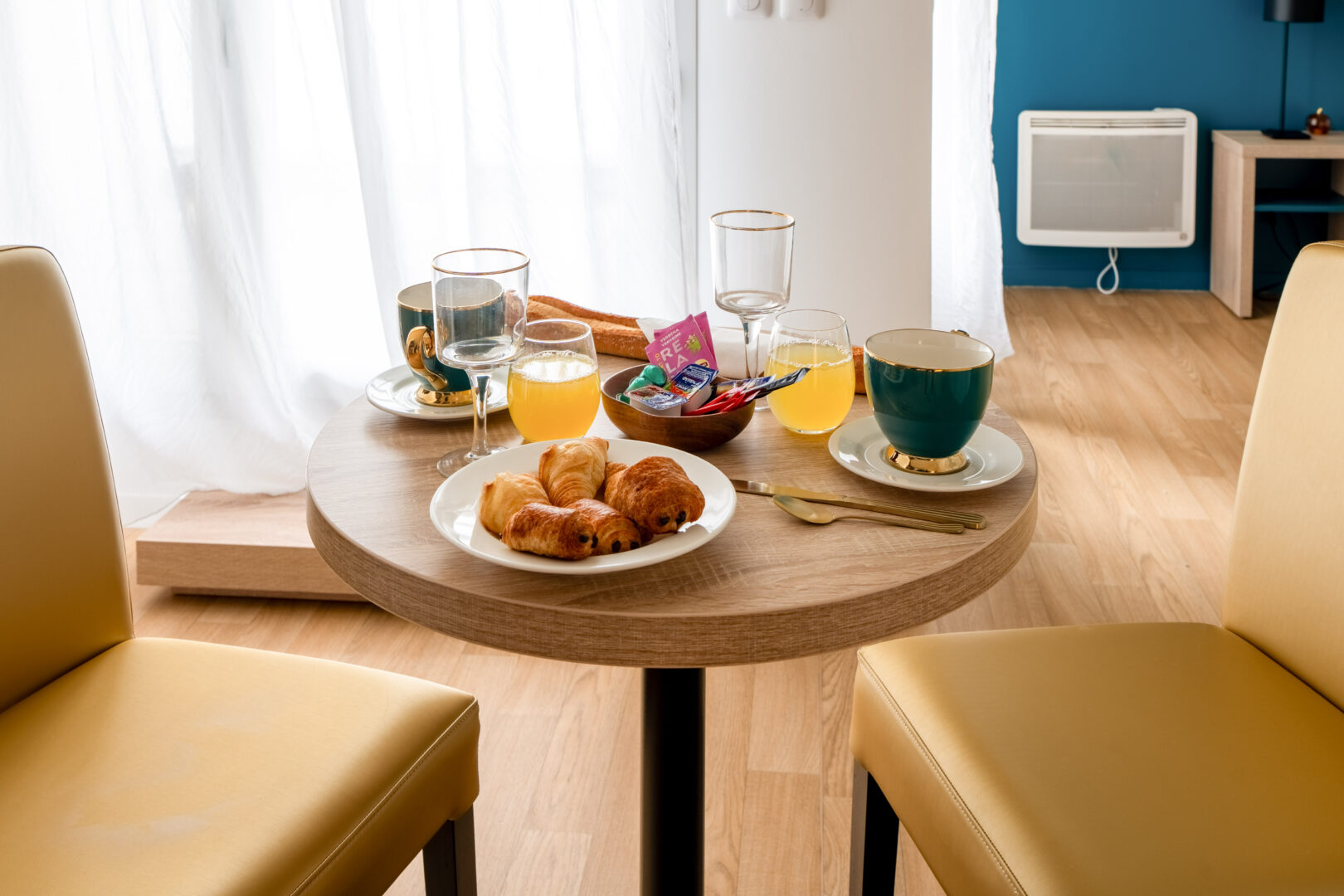 Petit déjeuner servi sur une table ronde avec boissons et viennoiseries.