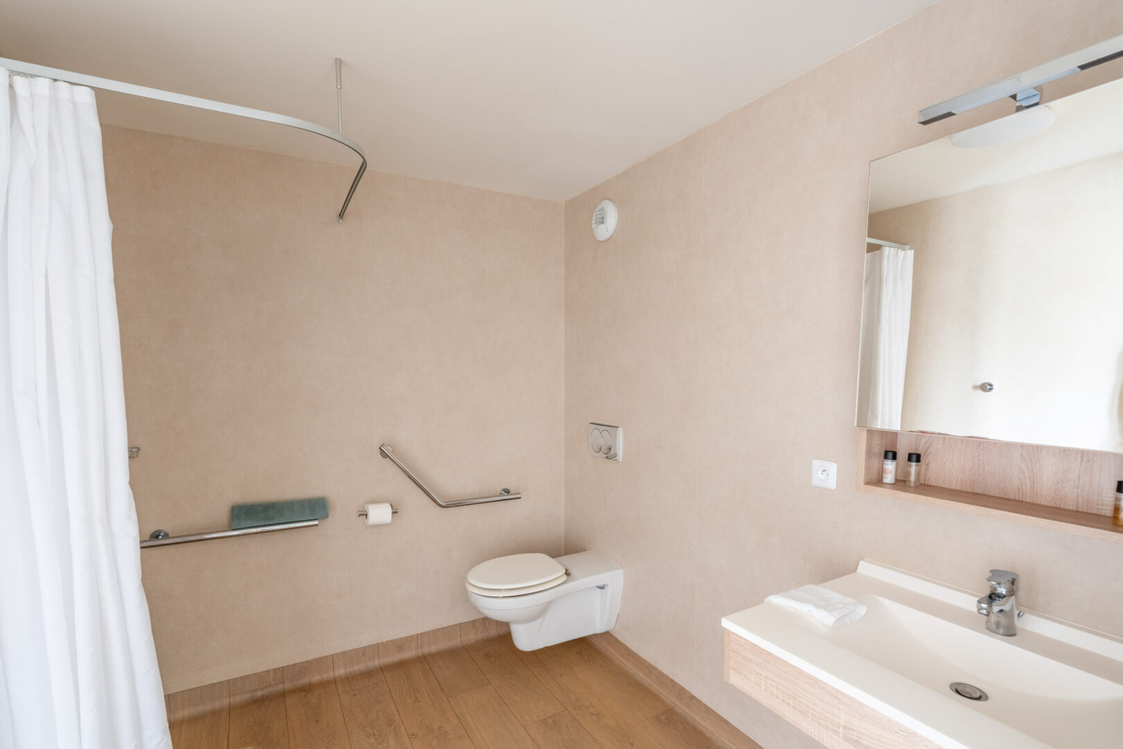 Salle de bain adaptée PMR avec douche italienne, WC surélevé et barre d’appui.