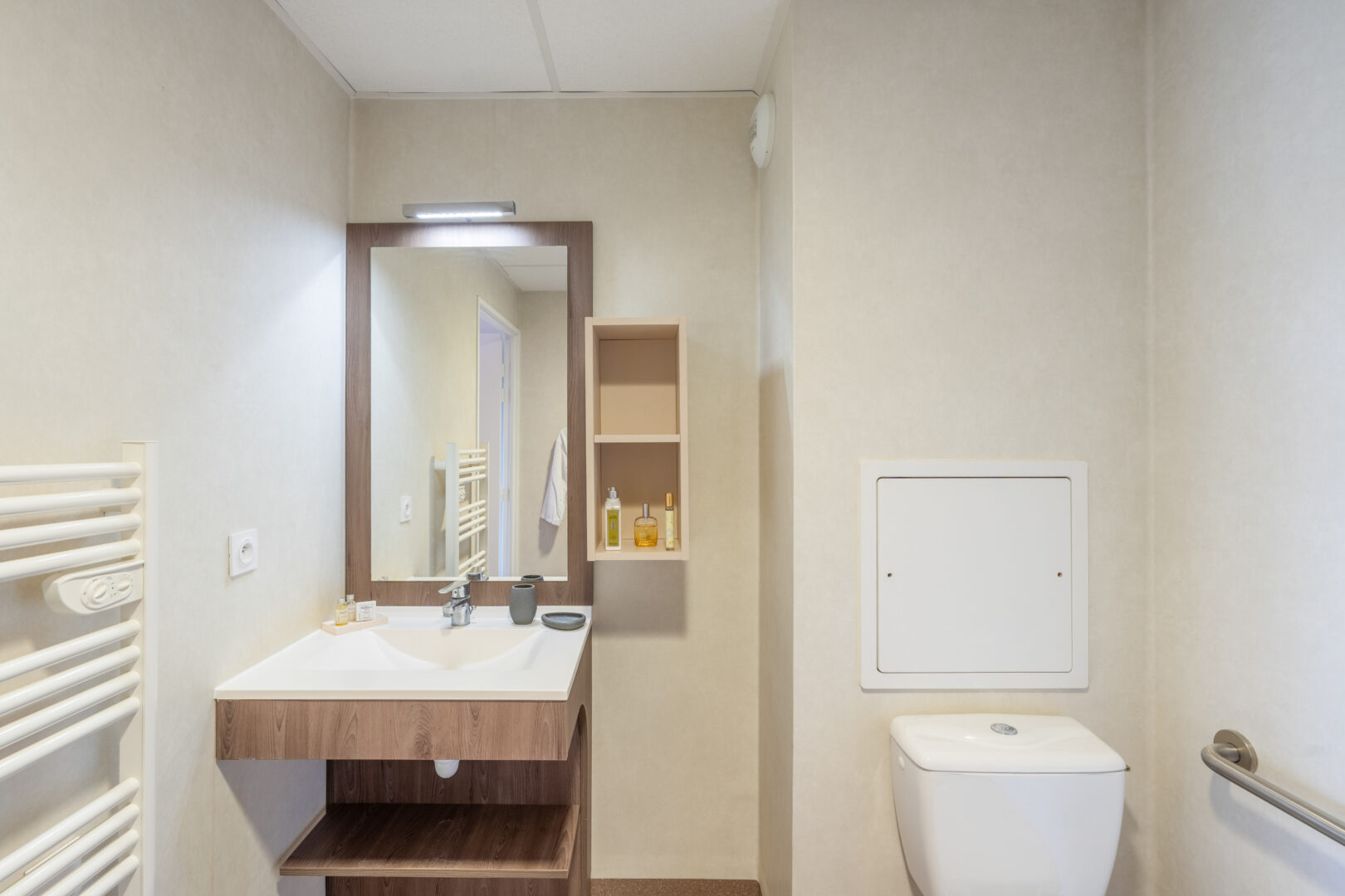 Salle de bain moderne avec lavabo, miroir, WC et rangements.