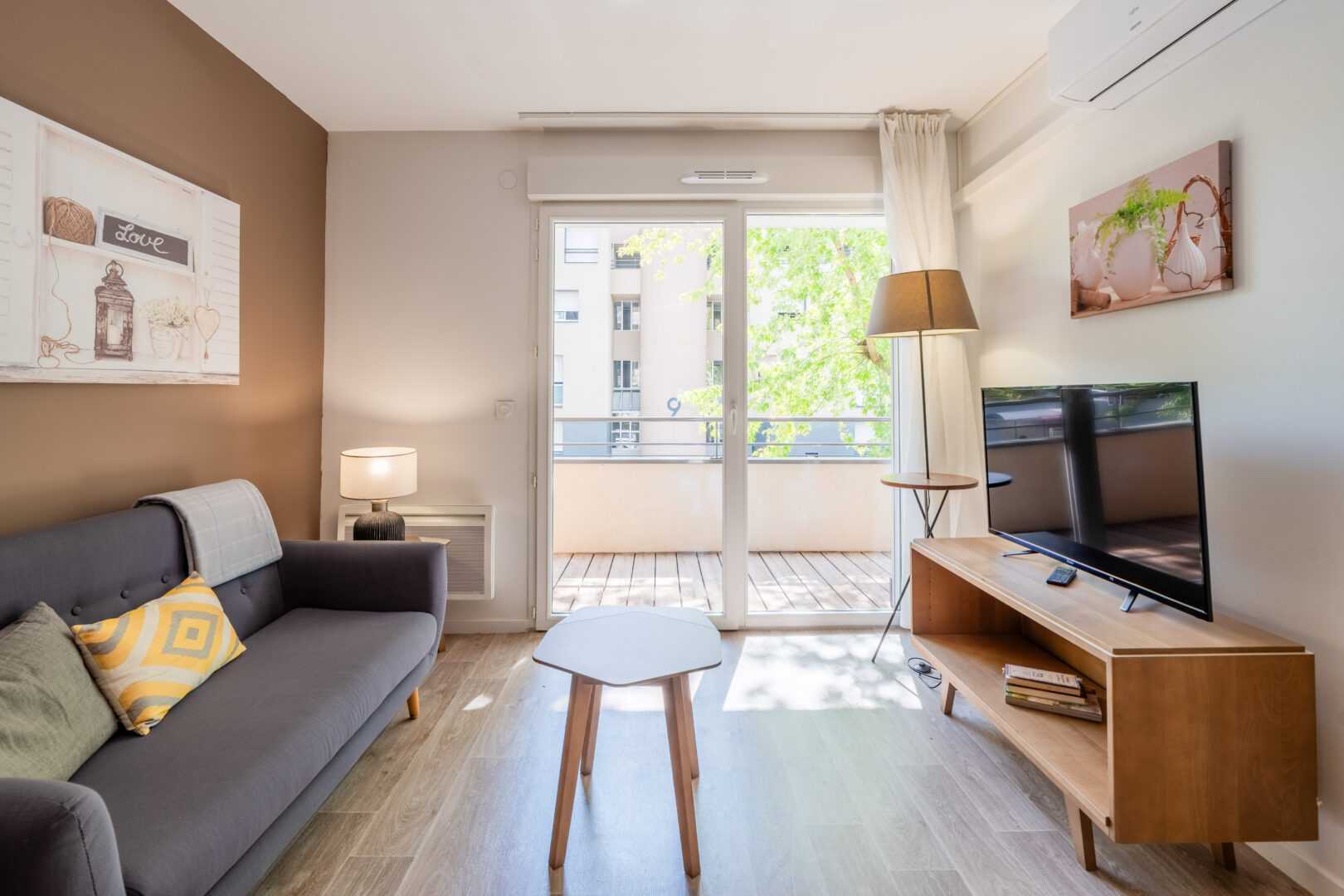 Salon moderne avec canapé, table basse et grande baie vitrée ouvrant sur un balcon.