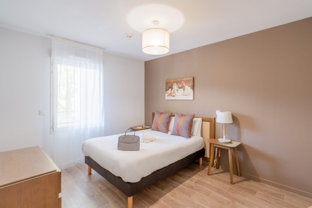 Chambre double lumineuse, coussins colorés et déco chaleureuse.