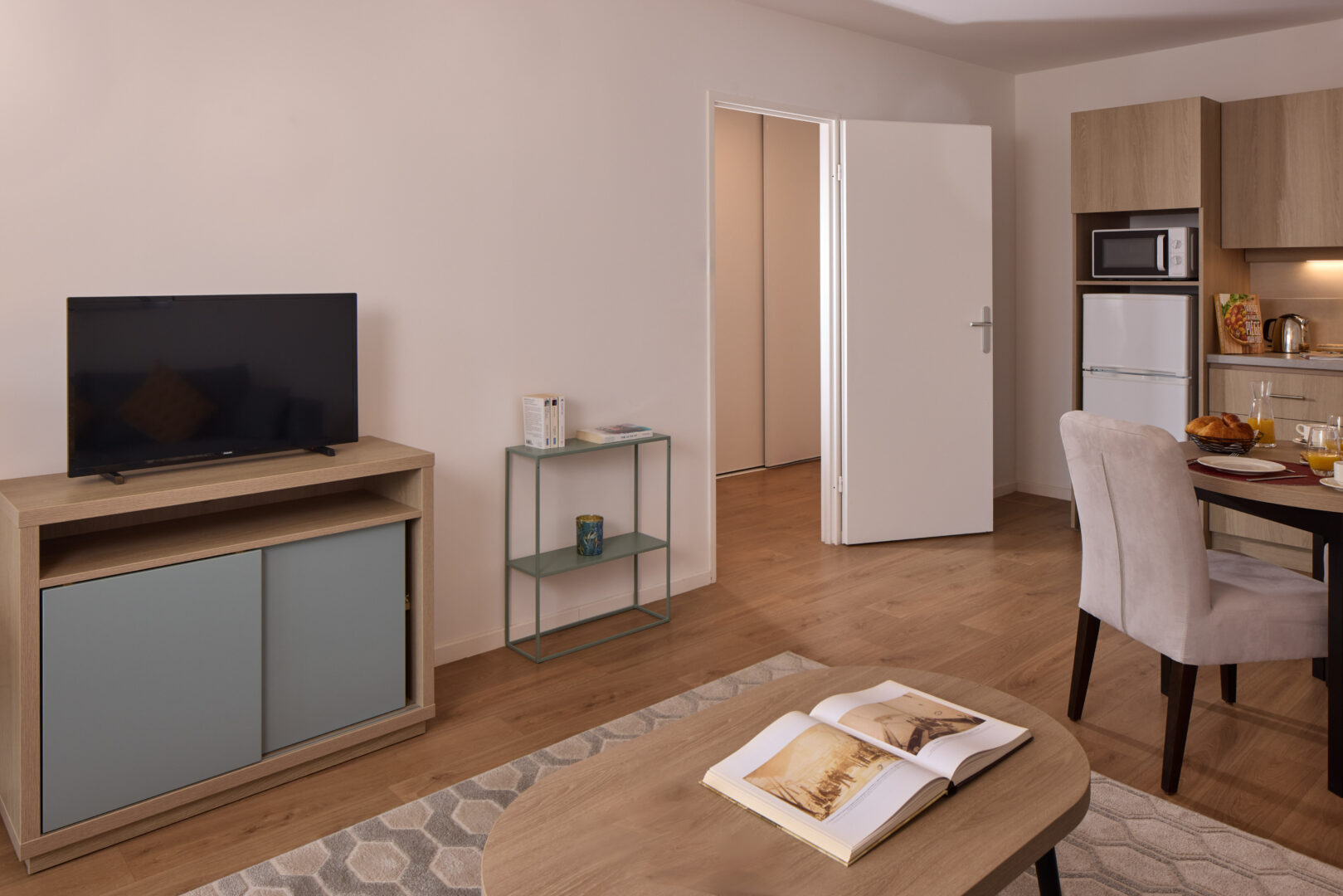 Salon moderne avec canapé, télévision, table basse et livre ouvert.