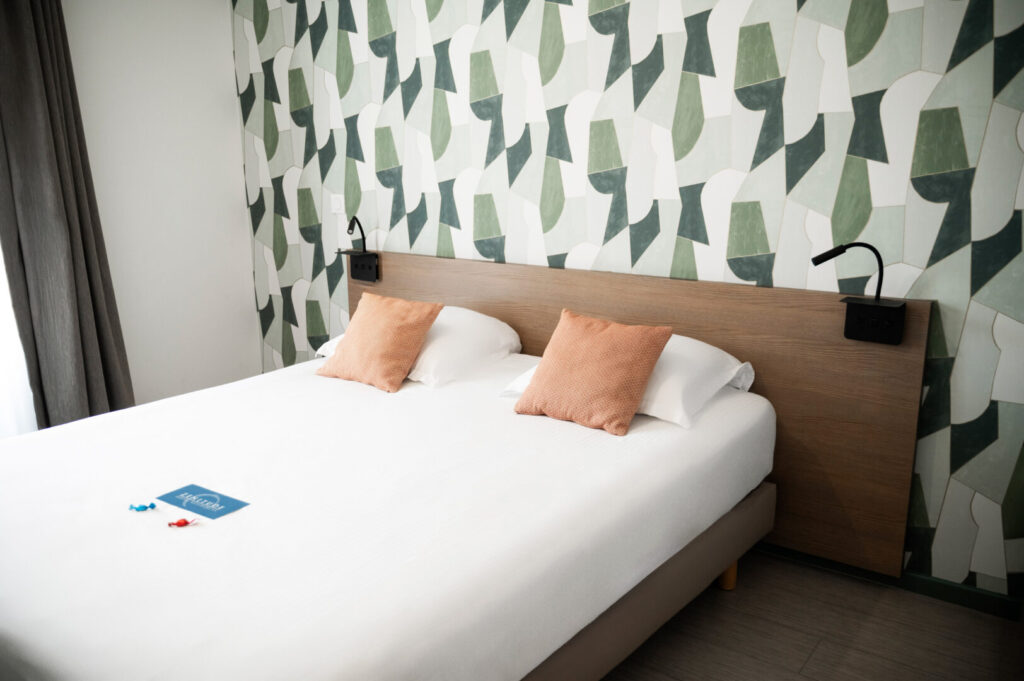 Chambre avec lit double, coussins et tête de lit en bois.