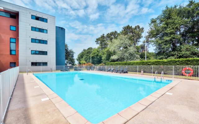 Piscine extérieure Zenitude Hôtel-Résidences Bordeaux - Aéroport avec transats et verdure