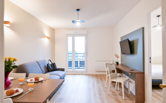 Espace de vie avec canapé et table repas.