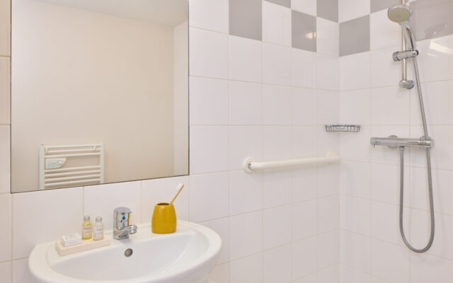 Salle de bain contemporaine avec douche à l’italienne, lavabo et barre d’appui.