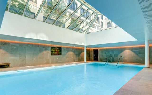 Piscine intérieure avec toit vitré et design contemporain.