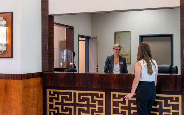 Réception avec comptoir en bois, personnel accueillant et décoration raffinée.