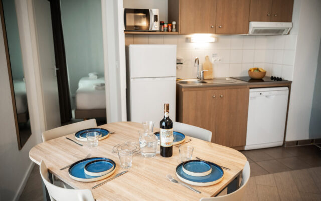 Kitchenette équipée avec coin repas et table dressée.