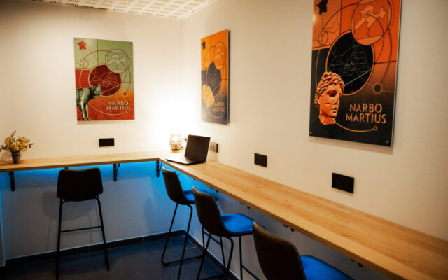 Espace de coworking avec bureau d'angle en bois et chaises hautes.