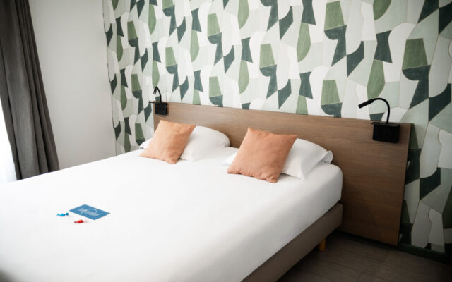 Chambre avec lit double, coussins et tête de lit en bois.