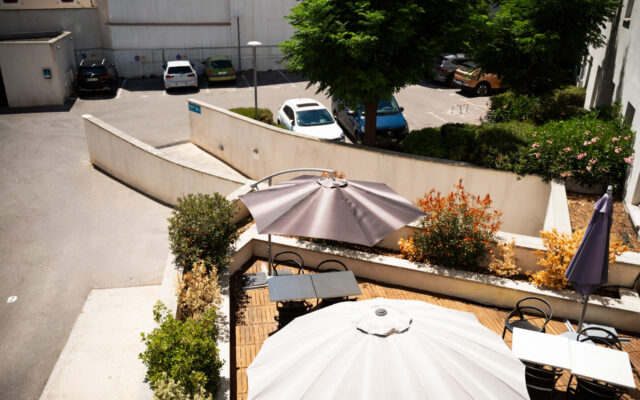 Terrasse extérieure avec parasols, plantes et mobilier.