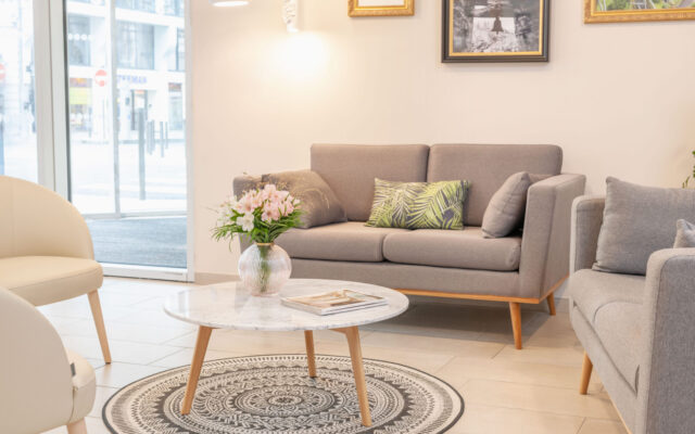 Espace lounge moderne avec canapé gris, table en marbre et décoration végétale.