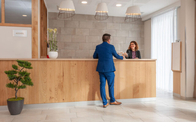 Réception moderne avec une réceptionniste en interaction avec un client.