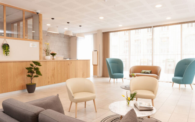 Hall d’entrée spacieux et lumineux avec coin salon et accueil en bois.