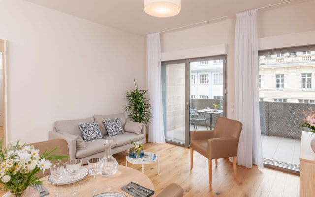 Salon lumineux d'un appartement Zenitude Hôtel-Résidences avec canapé, table à manger élégamment dressée et accès à un balcon aménagé